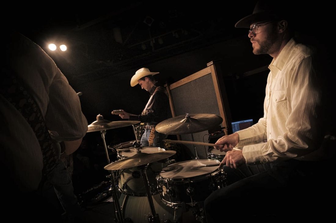 Drummer in a cowboy hat keeping time on stage